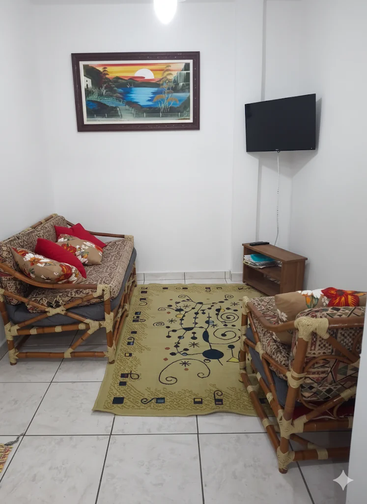 Sala de estar aconchegante do apartamento à beira-mar em Praia Grande com sofá, TV e decoração